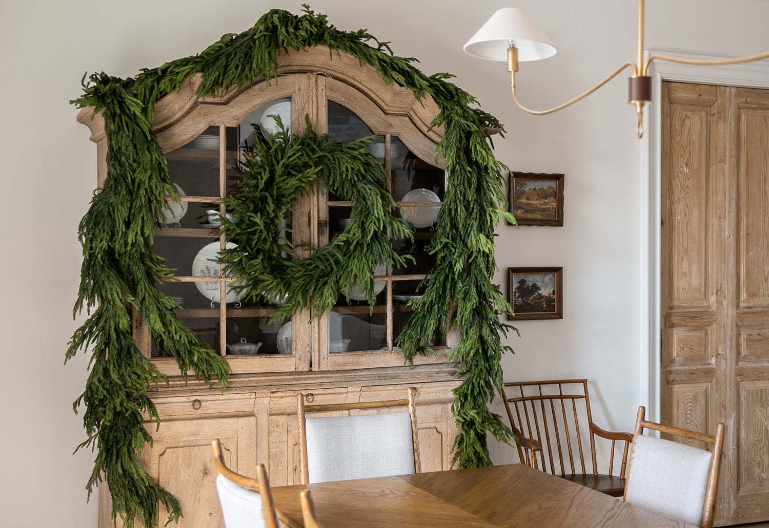 Dining room with a wooden hutch decorated with Afloral Norfolk Garland and Wreath