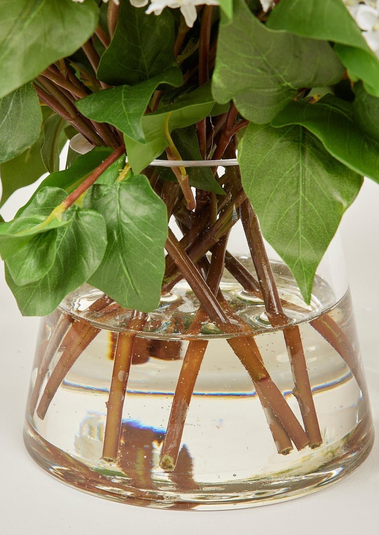 Glass Vase and Acrylic Water of Faux Lilac Arrangement in Afloral Closeup View