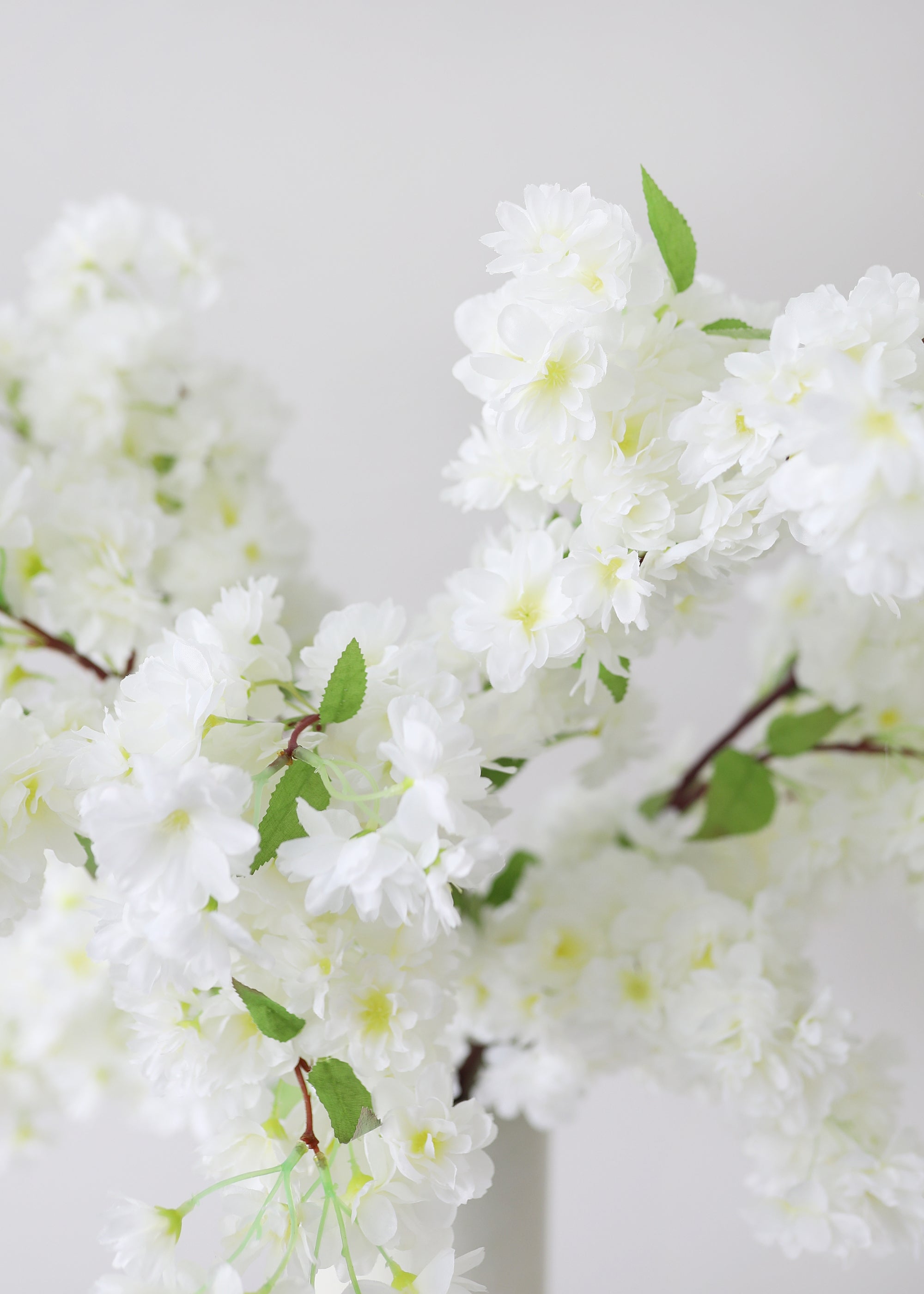 Artificial white cherry blossoms with green leaves