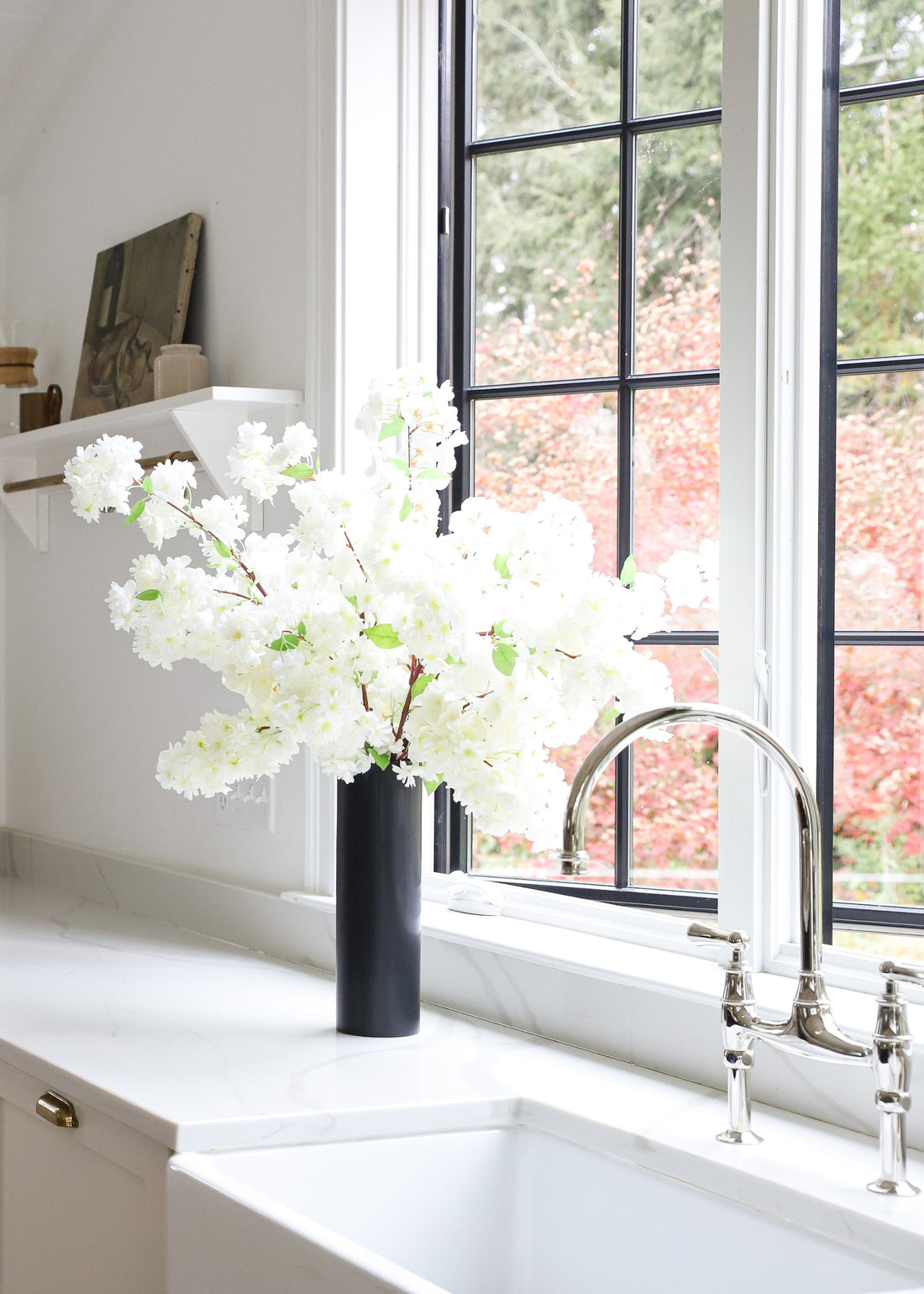 vase of white cherry blossoms on the kitchen counter