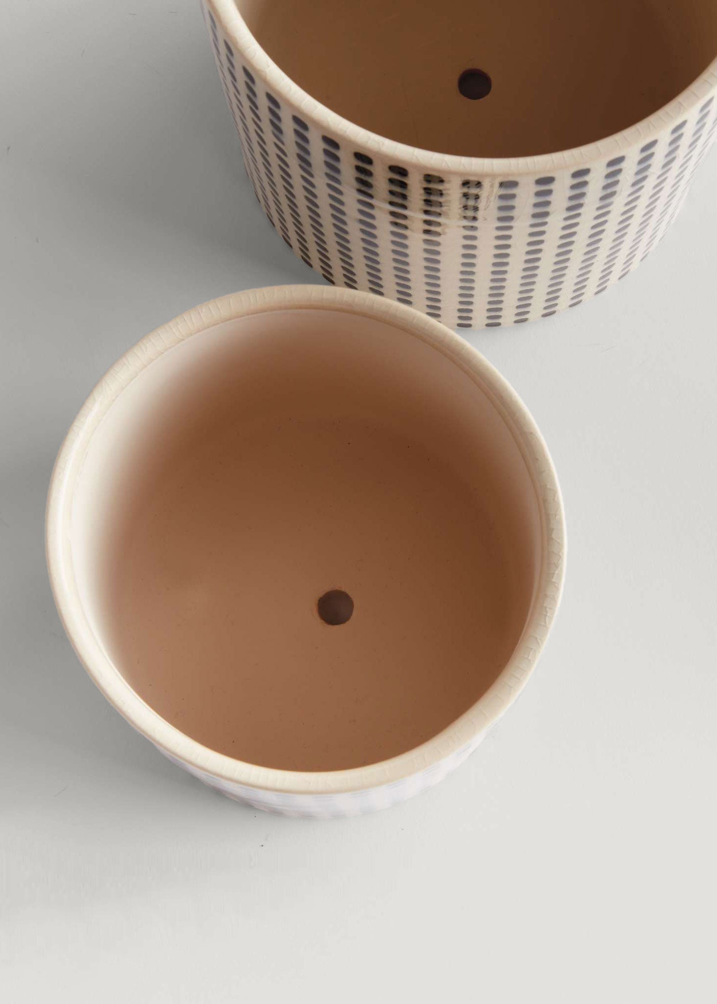 Openings of two ceramic pots with drainage holes