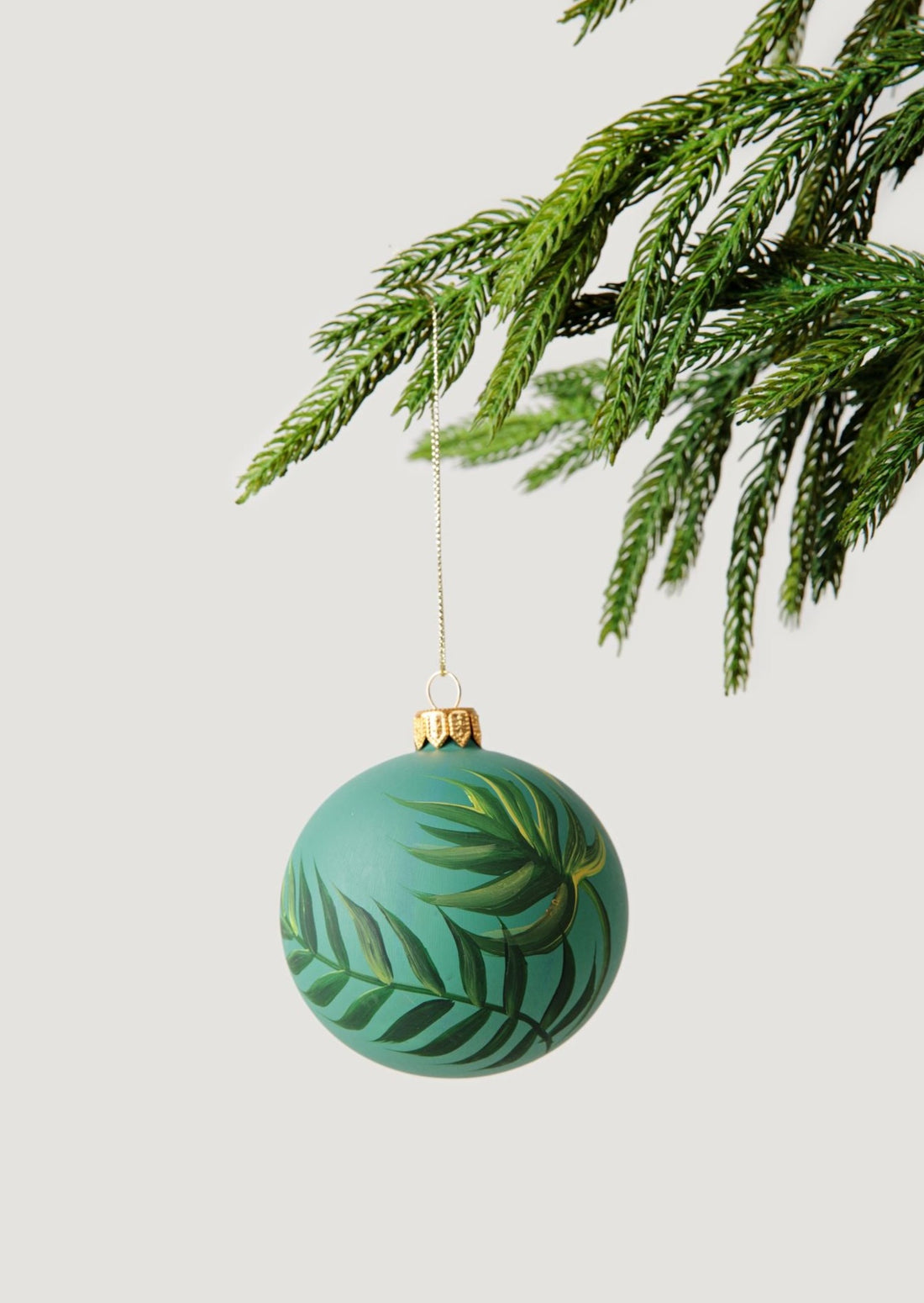 Green Palm Leaf Glass Christmas Ornament Shown on Faux Pine Tree Branch