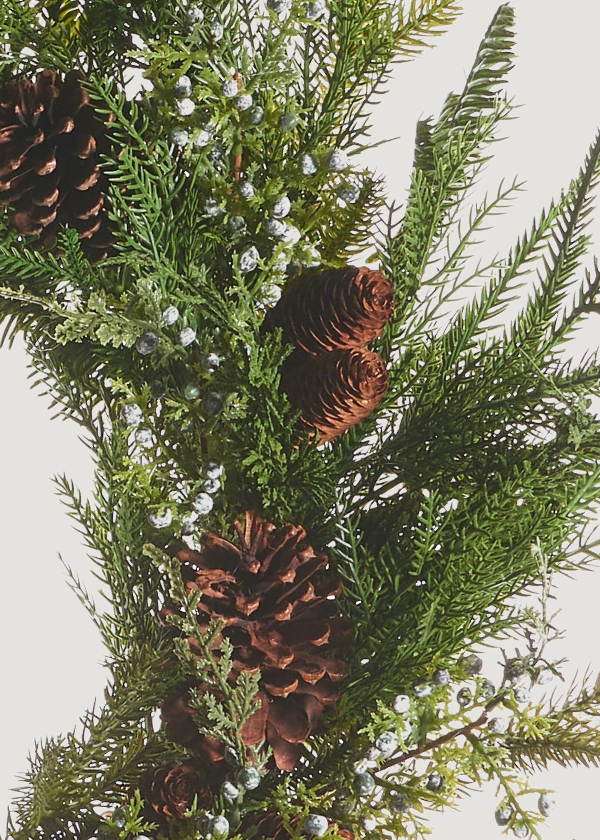 Close-up of a faux evergreen wreath with juniper berries and pine cones