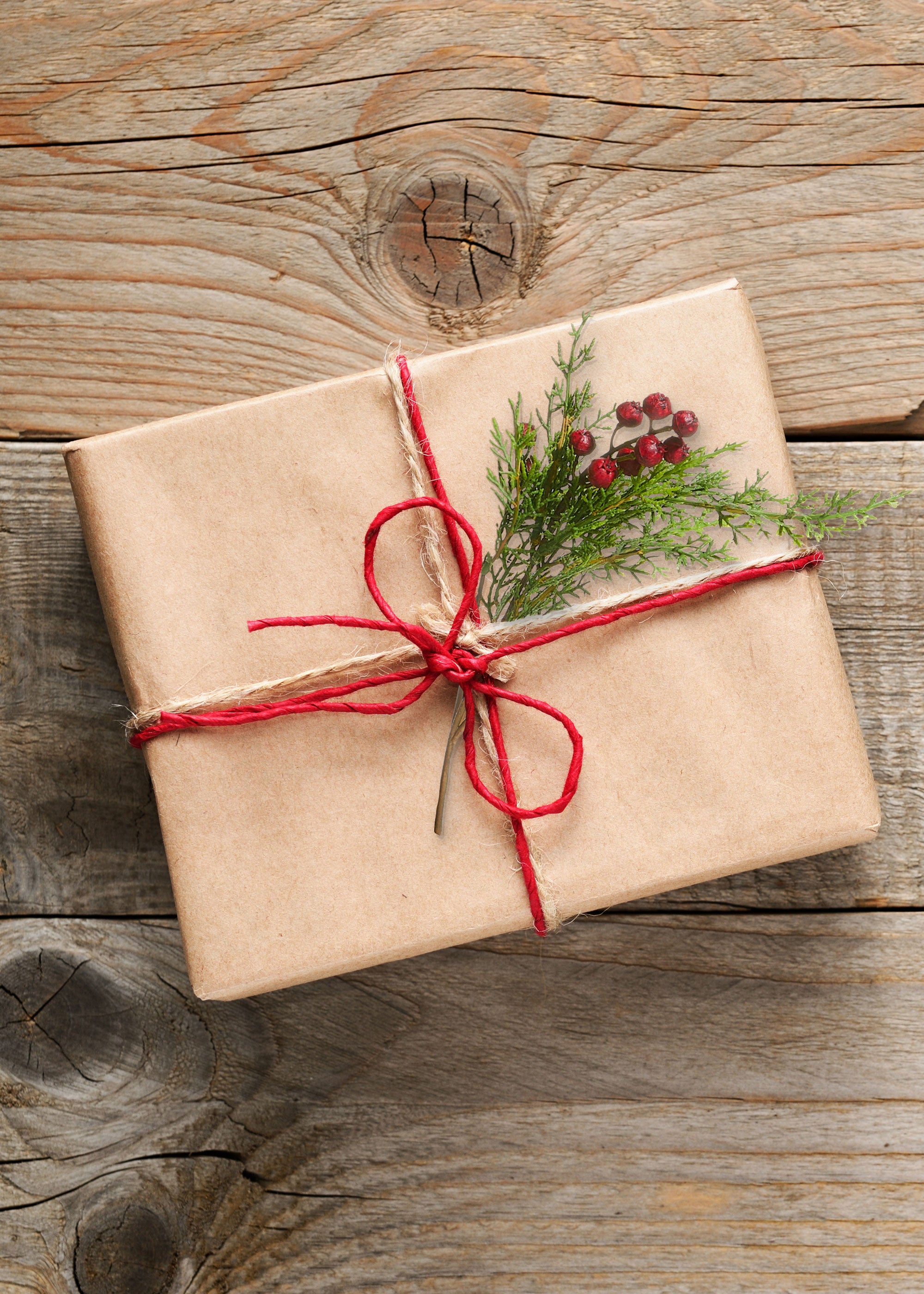 Brown paper package decorated with faux cedar and red berries