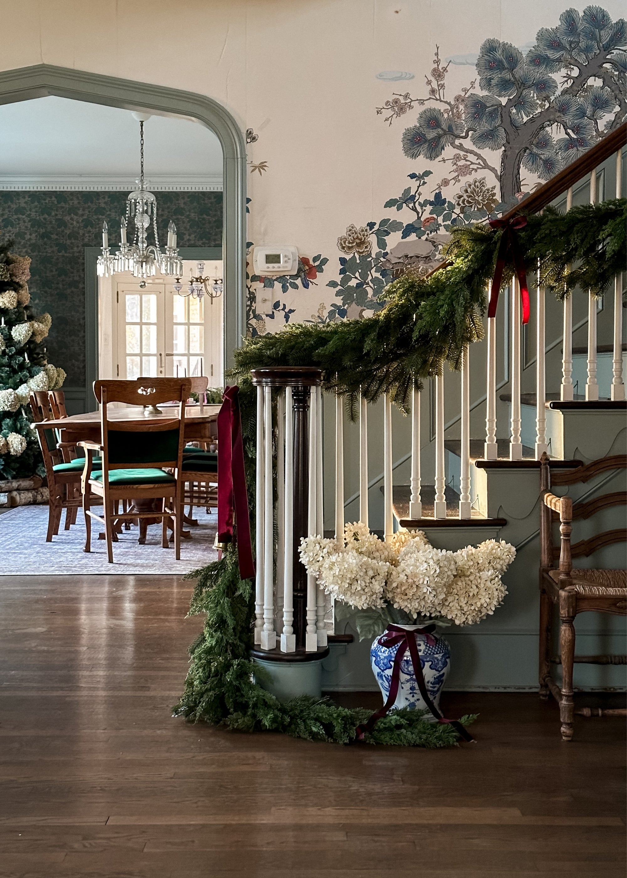 Decorative staircase with cedar greenery garalnd and a vase of parchment hydrangeas in a home
interior.