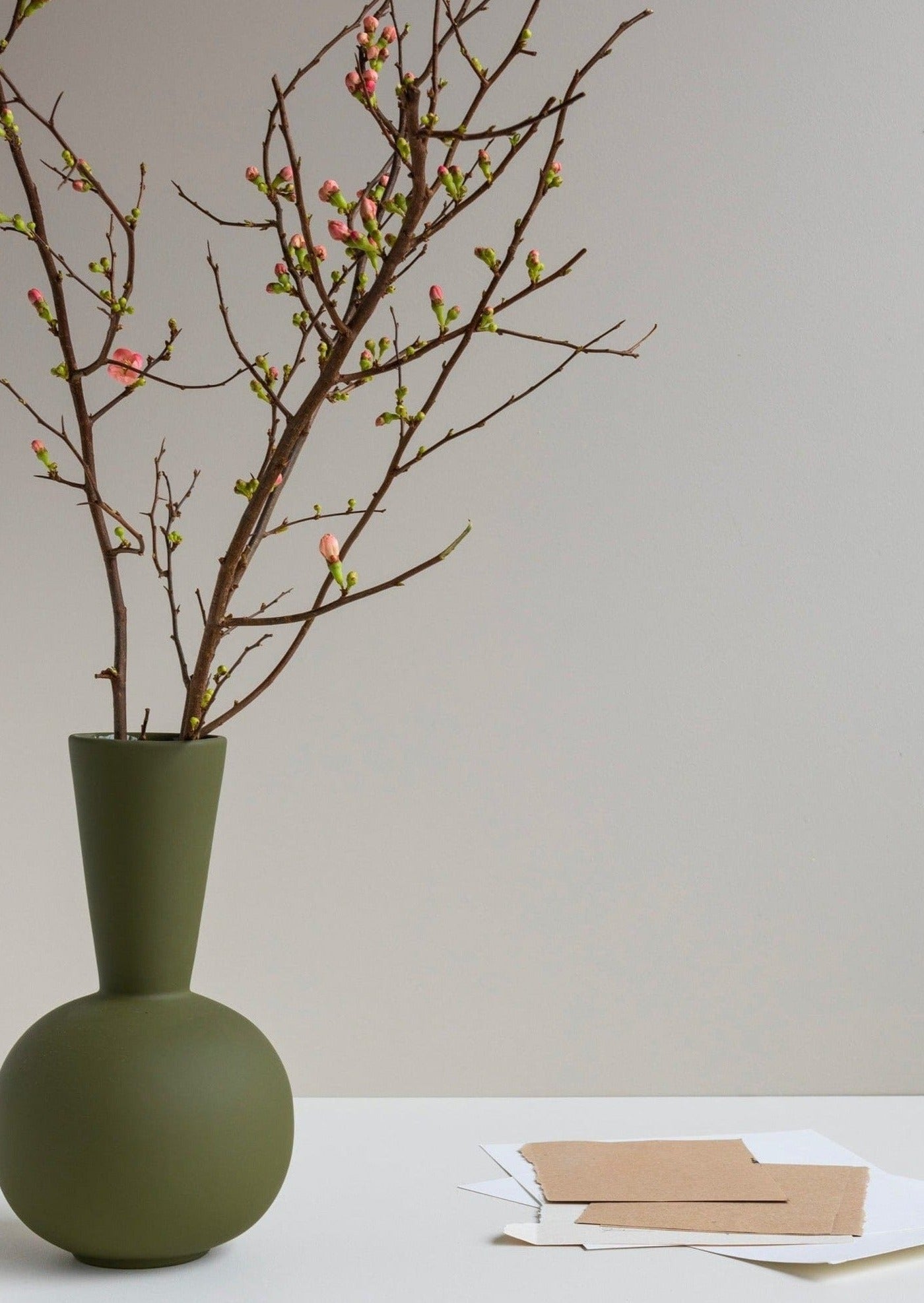 olive green ceramic vase styled with faux branches at afloral