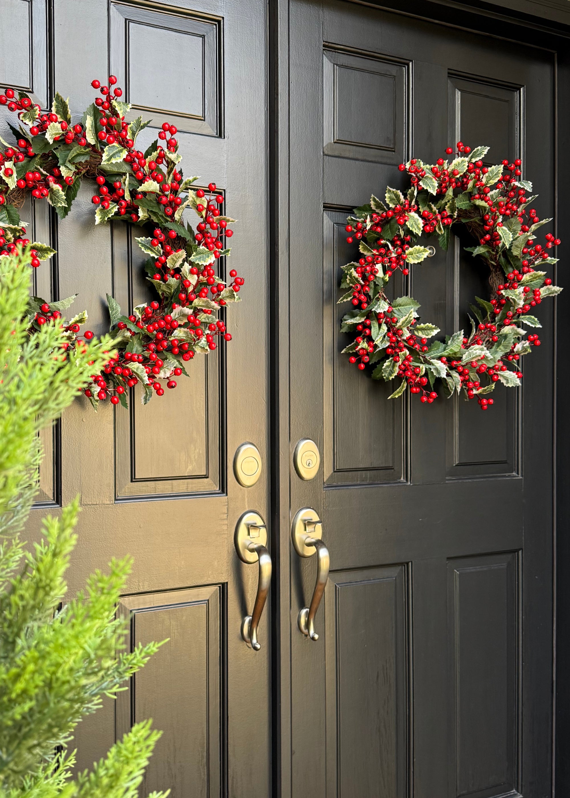 Decorative wreaths with red berries and holly on double doors