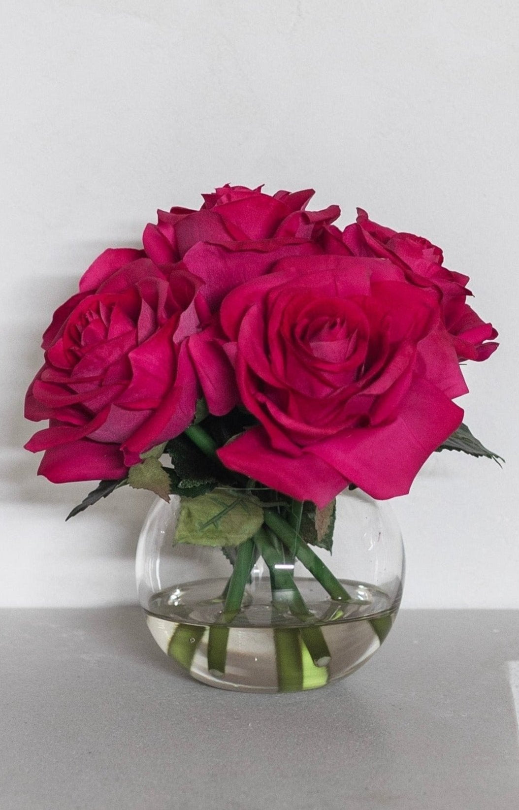 premade arrangement of fuchsia real touch roses styled on bathroom sink