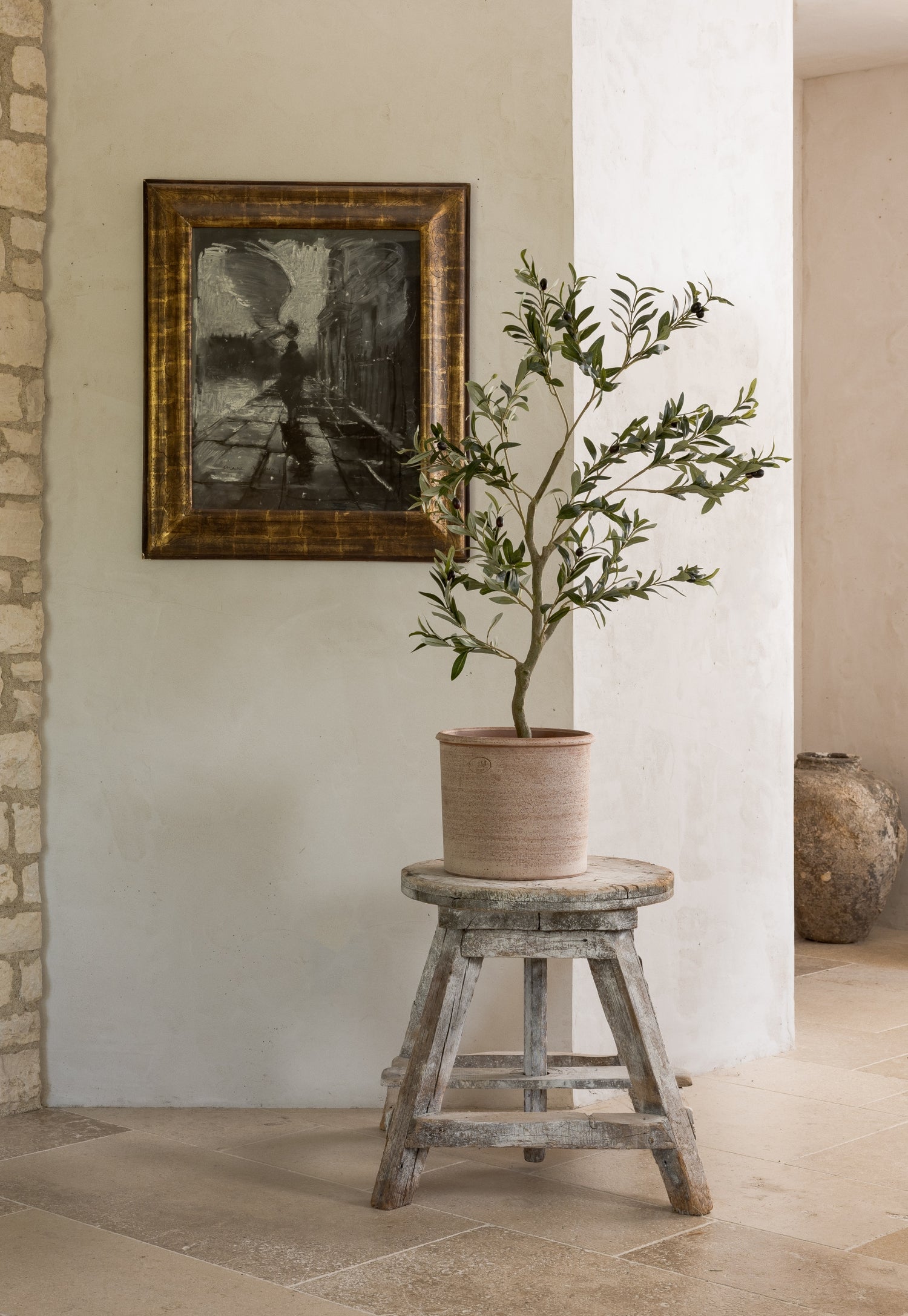 A clean faux olive tree placed on a stool. | Afloral