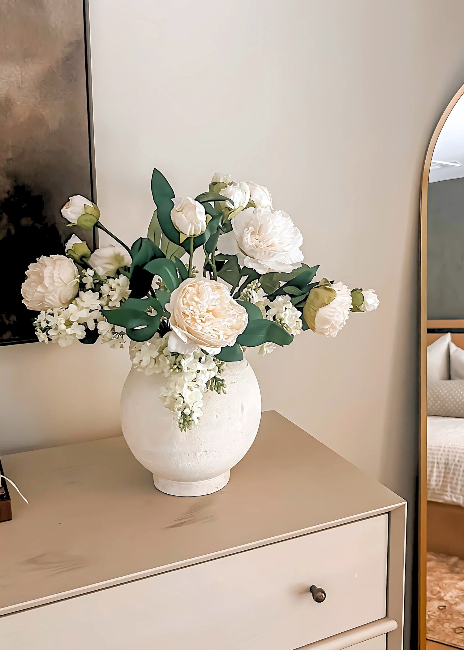 White vase with faux peony flowers on a dresser