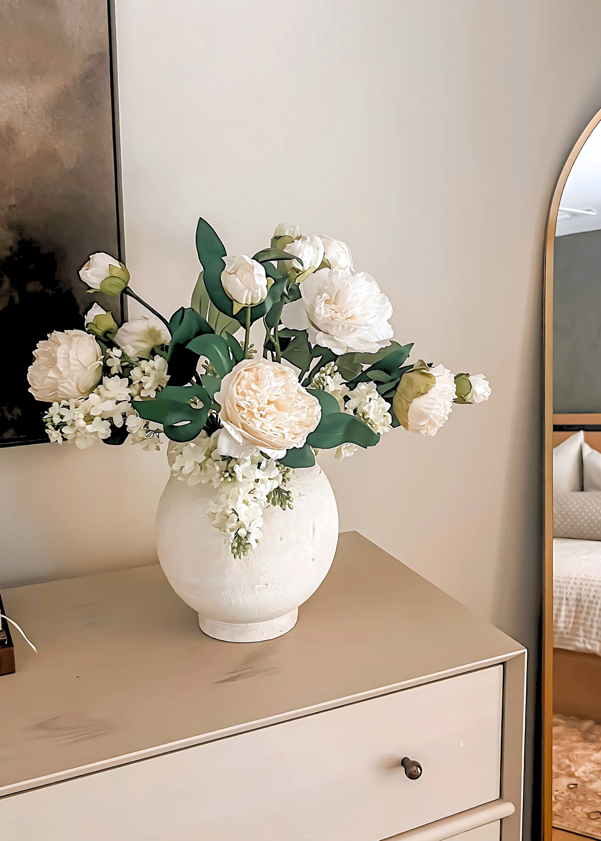 White vase with faux peony flowers on a dresser