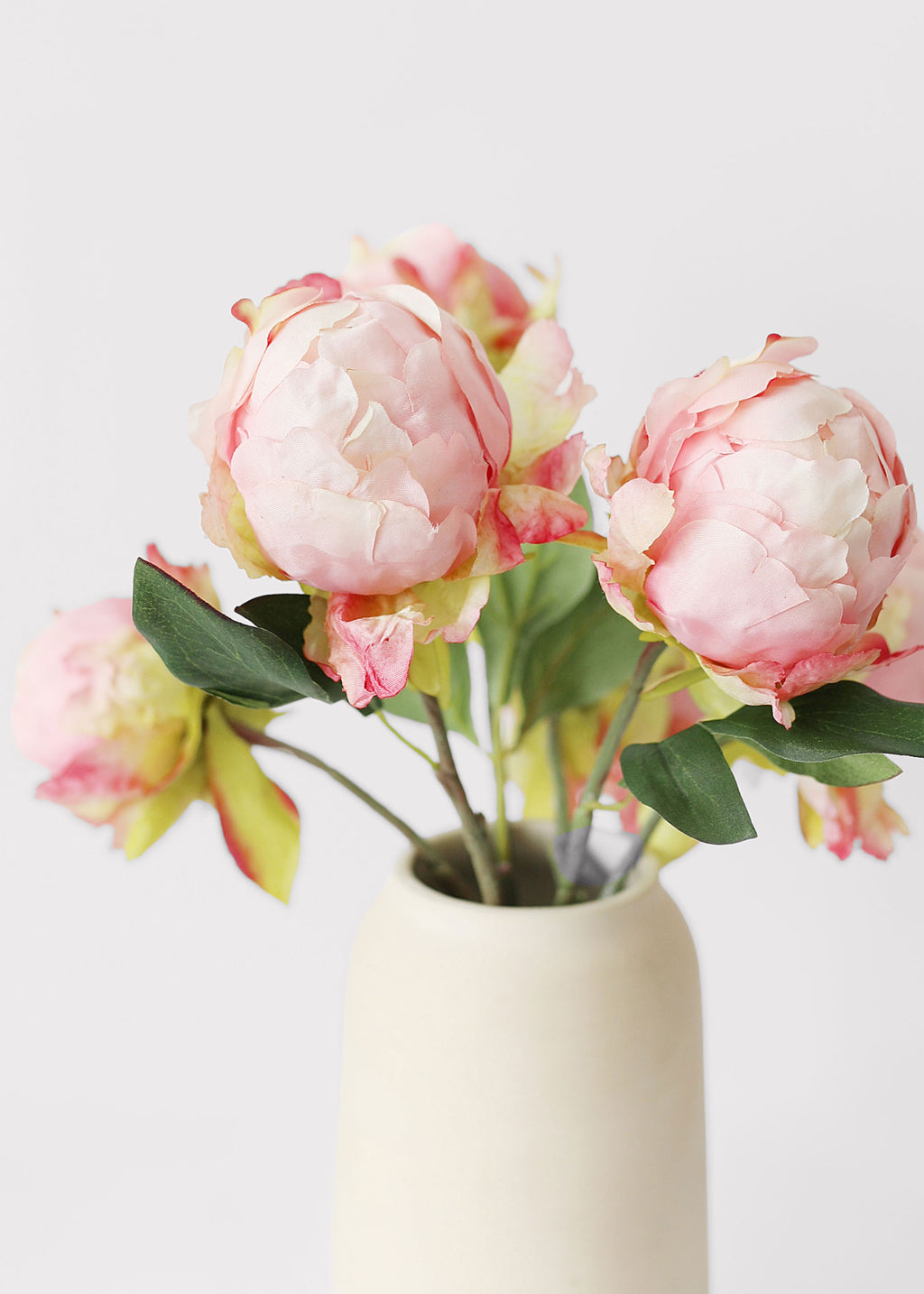 artificial peony buds arranged in a vase