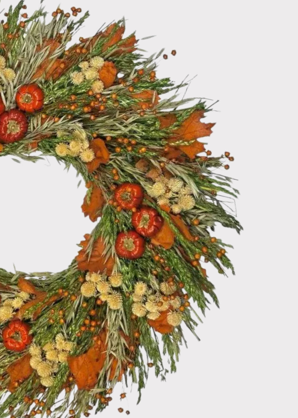 An autumn-themed floral wreath featuring orange pumpkins, dried maple leaves, sage green foliage, and small cream-colored flowers