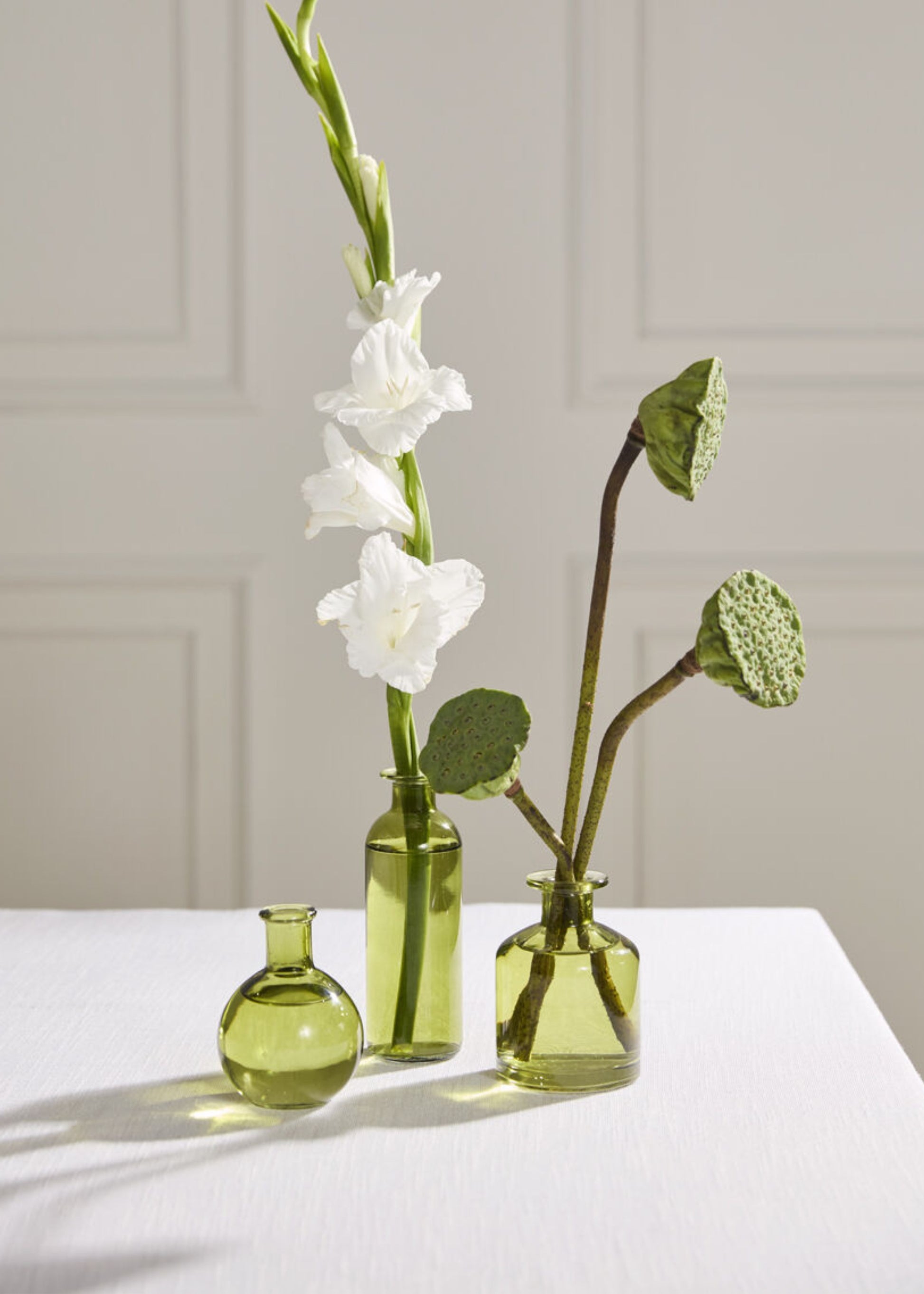 Three green glass bottles with flowers 