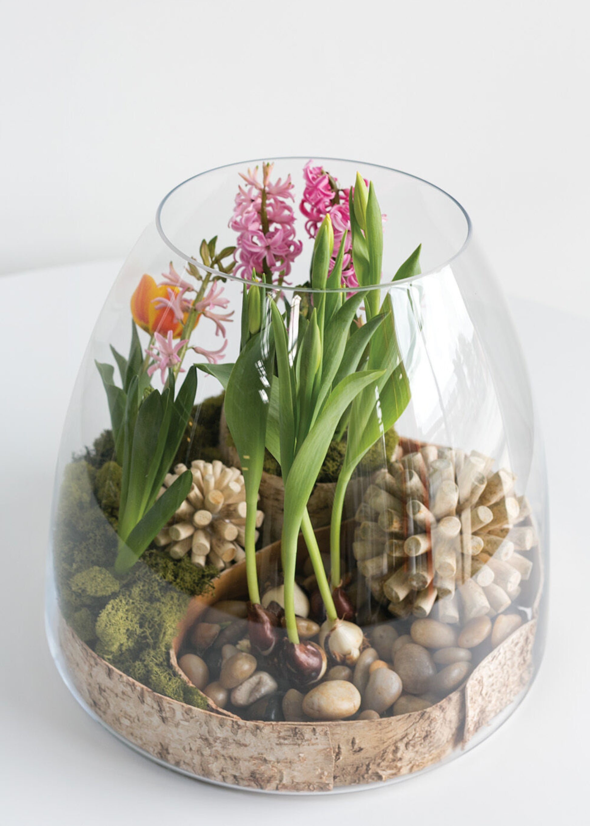 Glass terrarium with flowers and pebbles 
