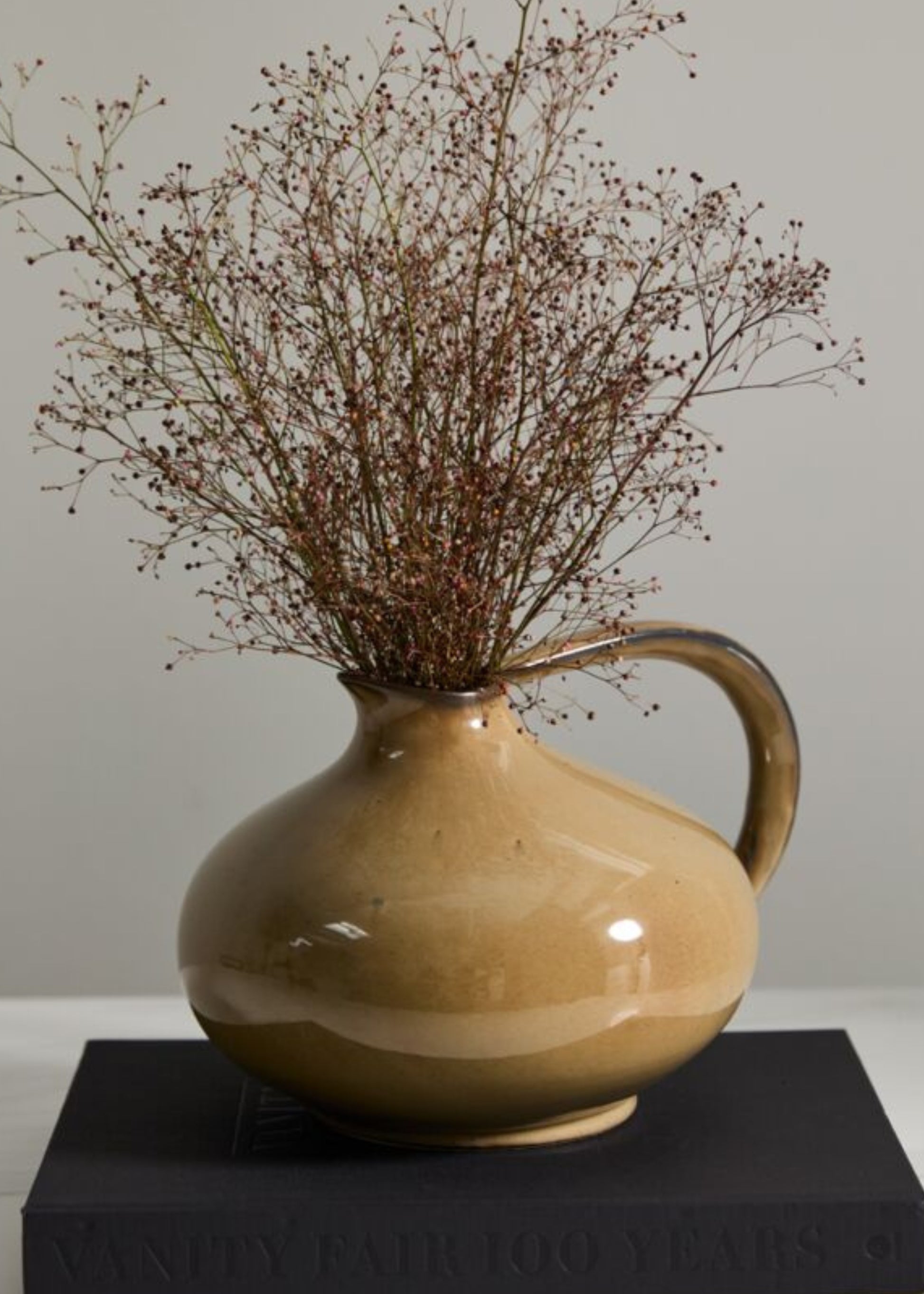 Beige ceramic pitcher with dried flowers 