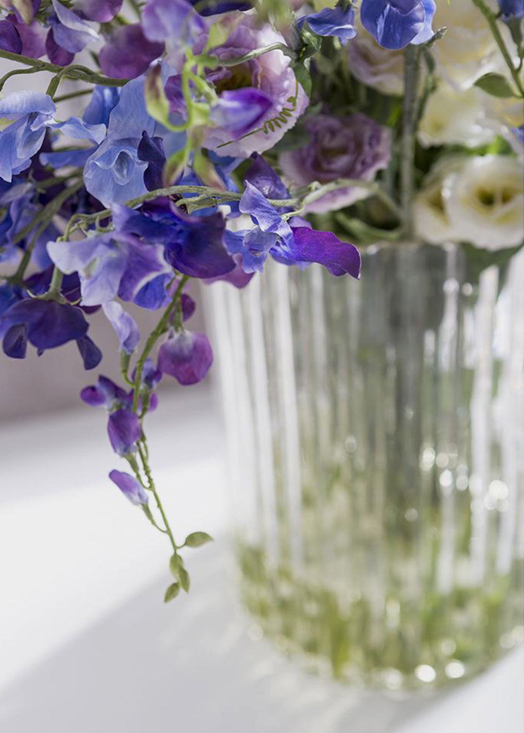 Clear glass vase with purple, blue, and white flowers
