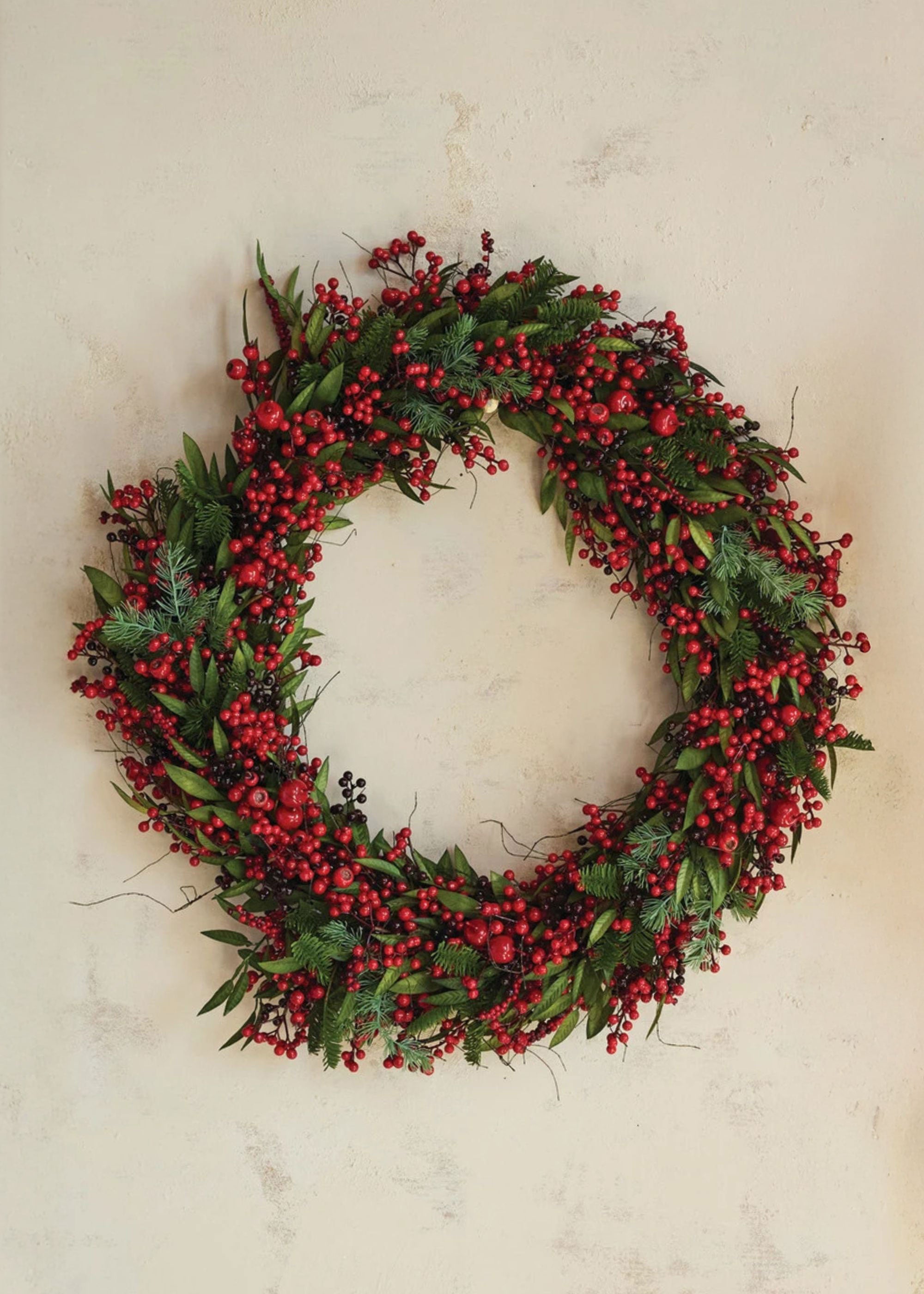 Christmas wreath with red berries and green leaves on a light background