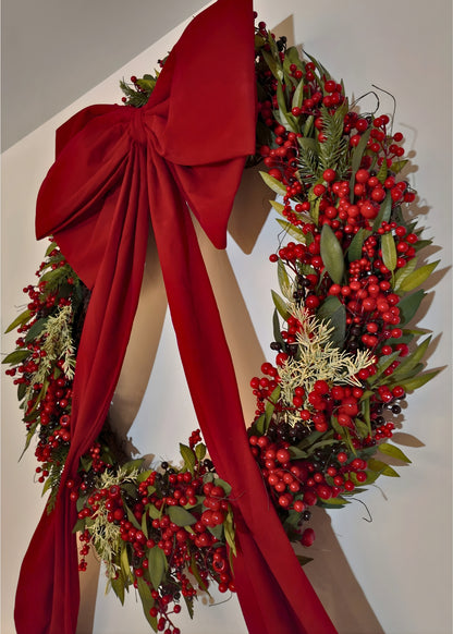 Christmas wreath with red berries and a large red bow 