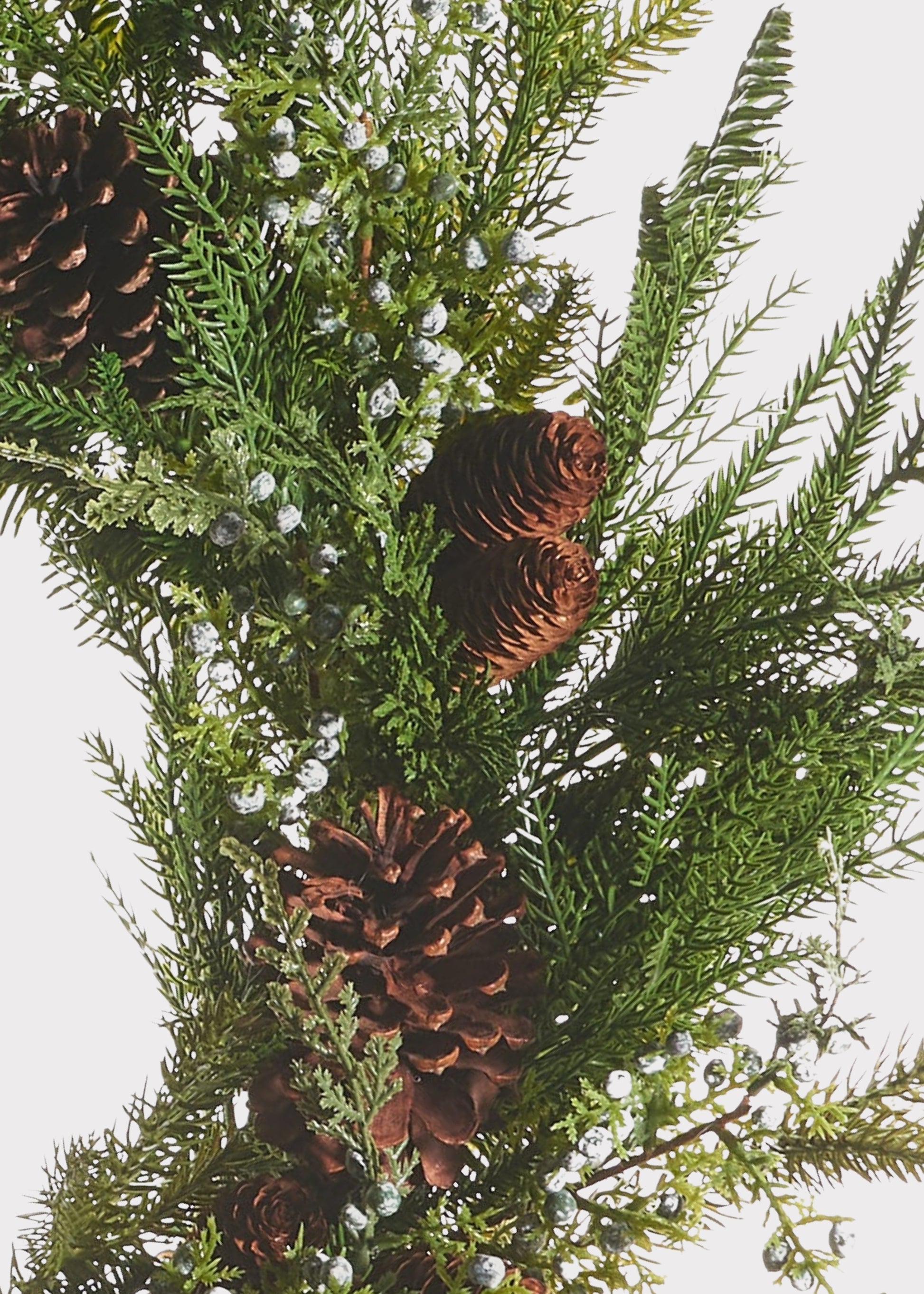 Close-up of a faux evergreen wreath with juniper berries and pine cones