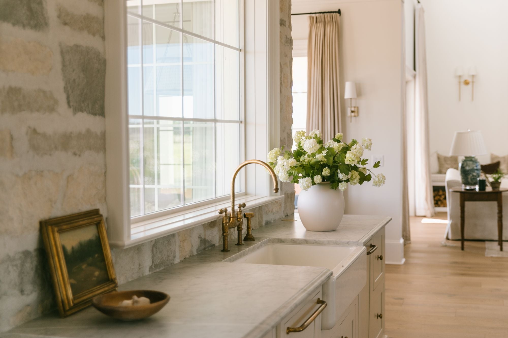 Modern kitchen with marble countertop, gold fixtures, and a vase of  faux flowers.