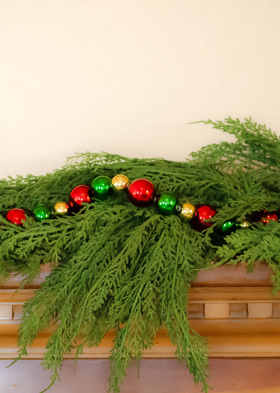 holiday bead garland on a mantel with faux cedar