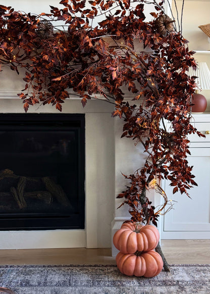 Decorative fall cimicifuga garland with pumpkins on a fireplace mantel.