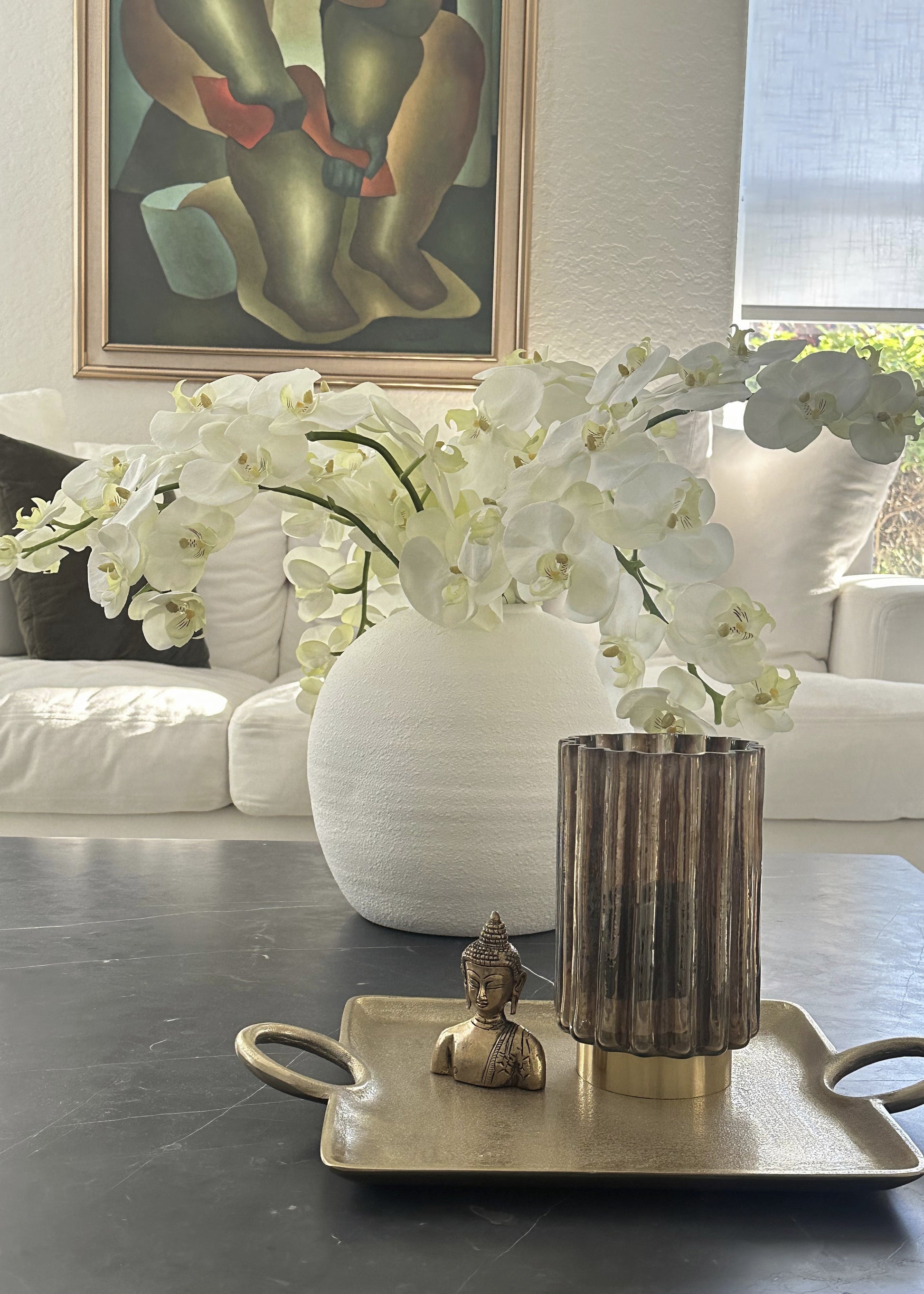 Decorative wall sconce with a vase of white flowers on a table, with a painting in the background.
