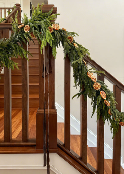 Stairail decorated with norfolk pine and orange slice garlands&quot;
