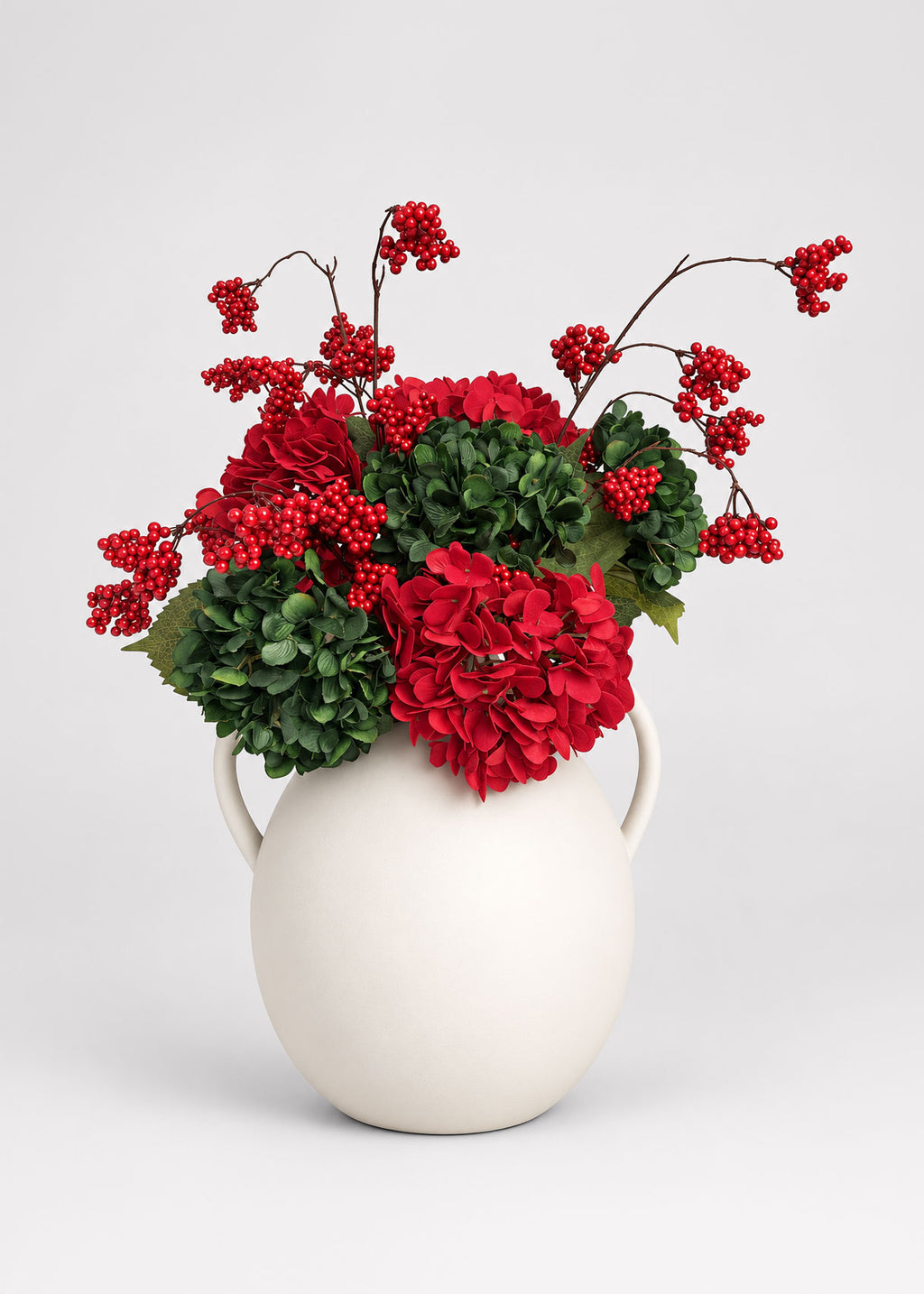 red and green hydrangea arrangement with red berries in the afloral white jug vase