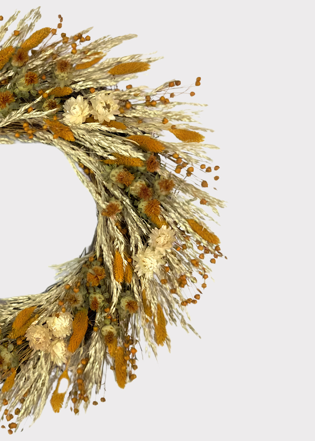 A dried floral wreath made of golden-orange grasses and cream flowers