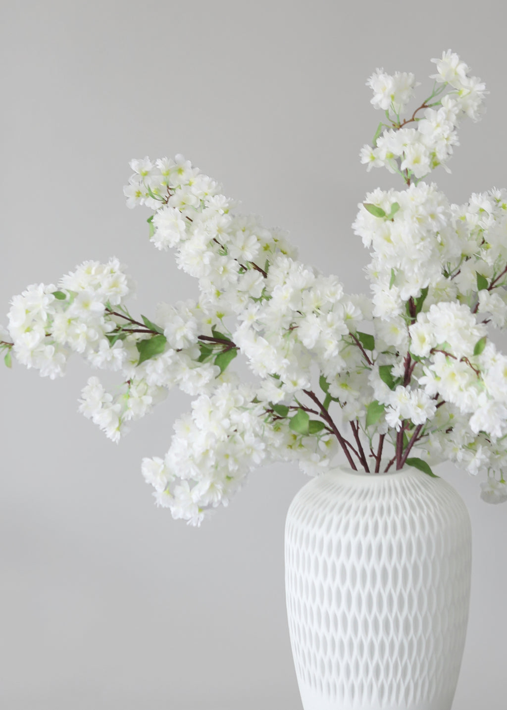 White cherry blossom flowers in a textured white vase