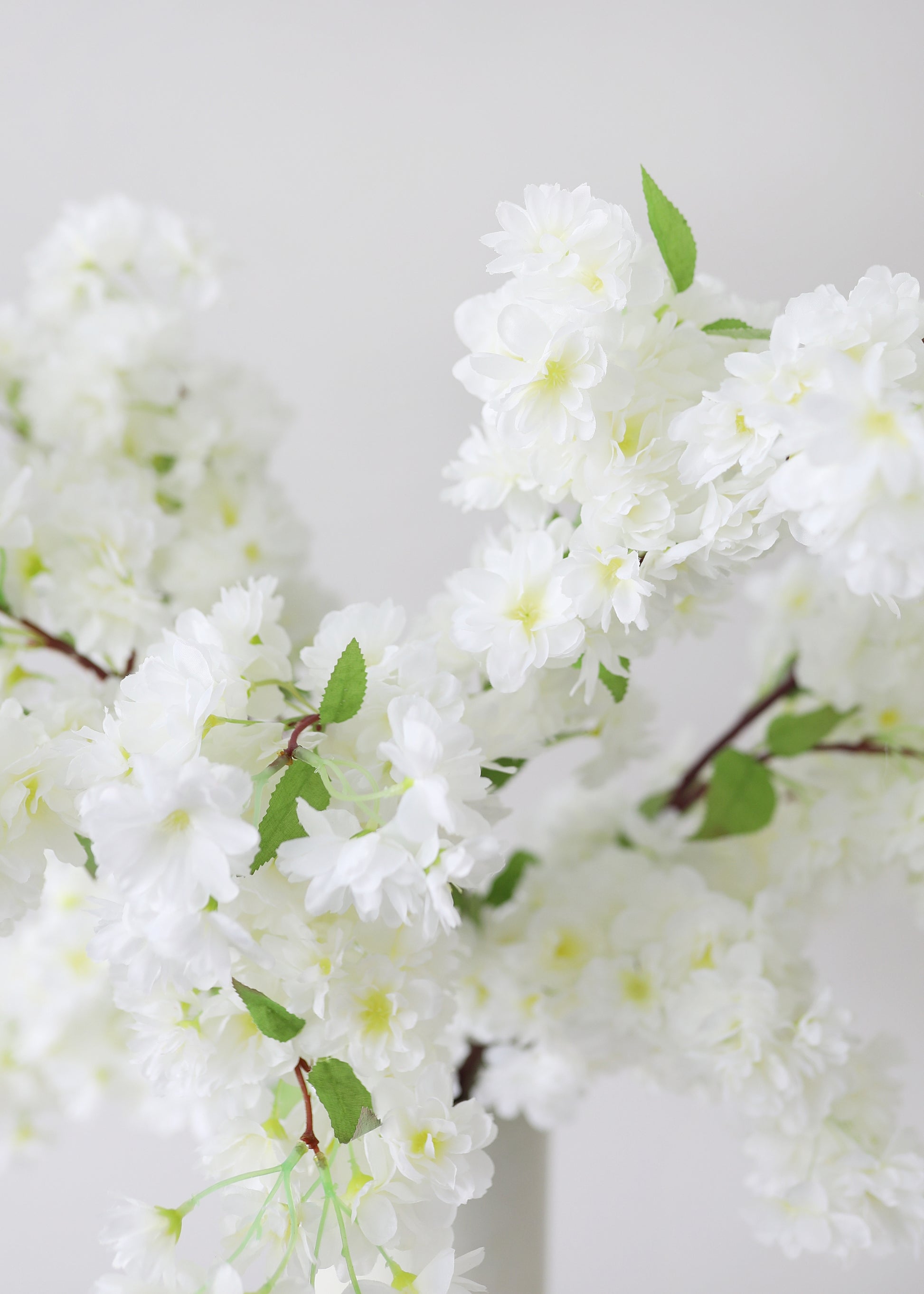 Artificial white cherry blossoms with green leaves 