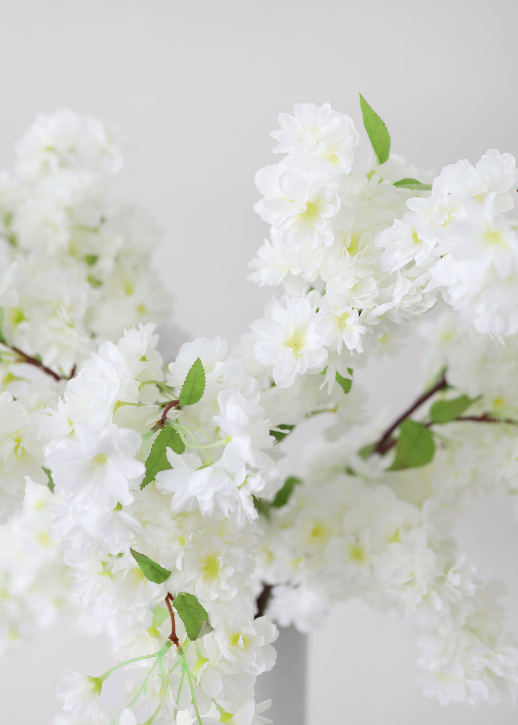 Artificial white cherry blossoms with green leaves 