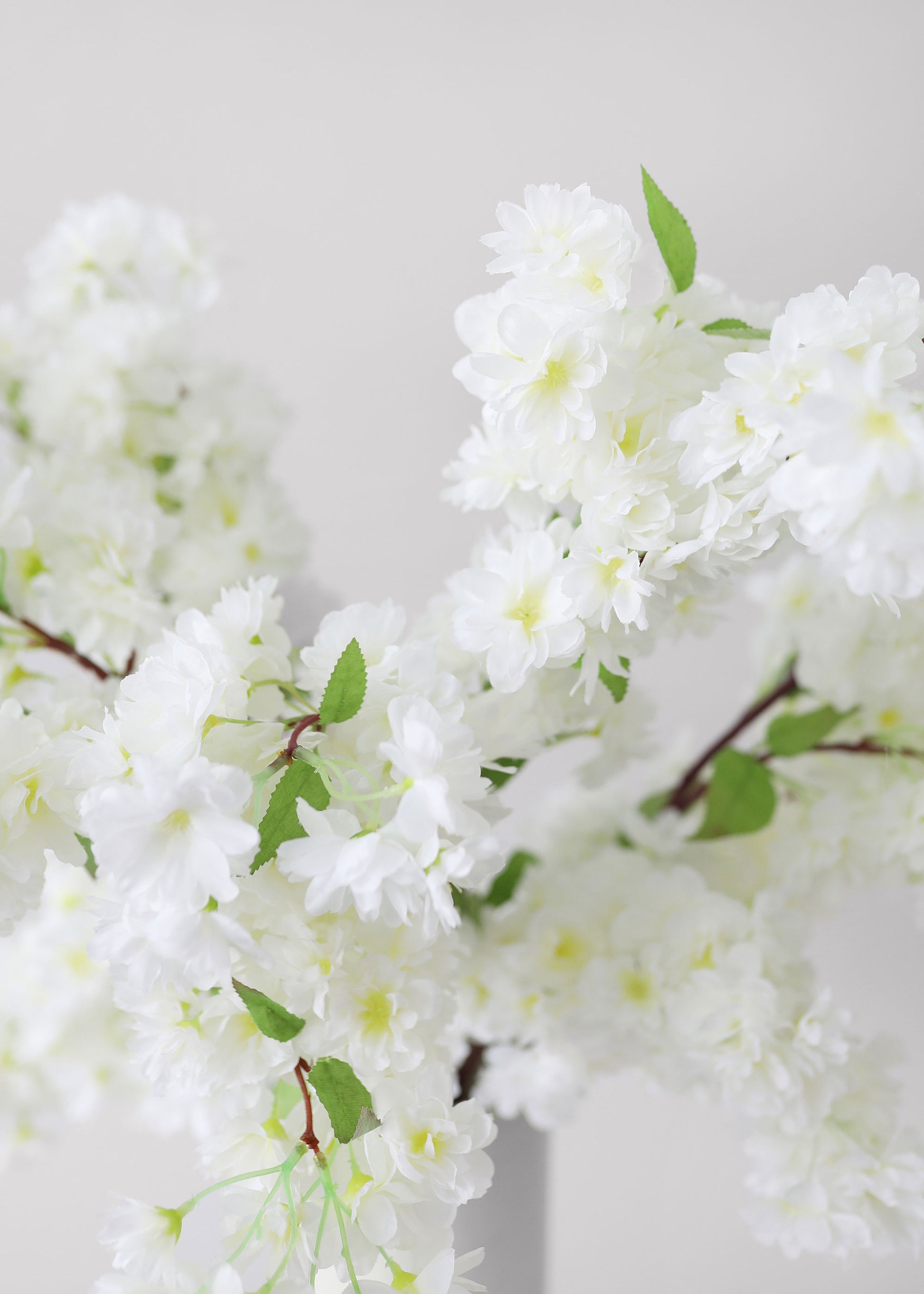 Artificial white cherry blossoms with green leaves 