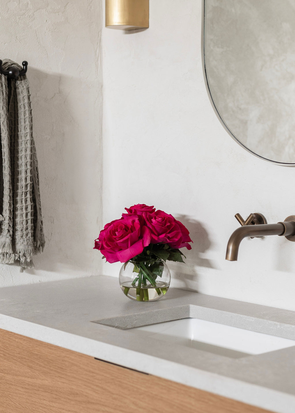 Bathroom counter with a vase of pink roses