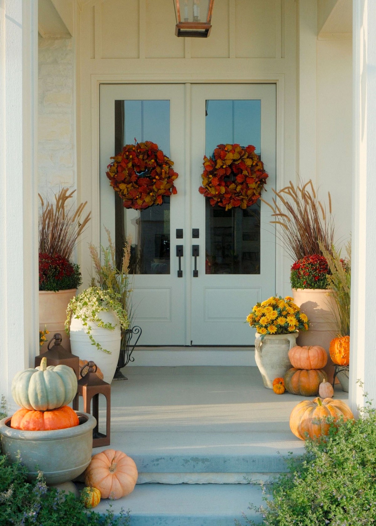 fall porch with outdoor mums, grasses, pumpkins and fall foliage wreath