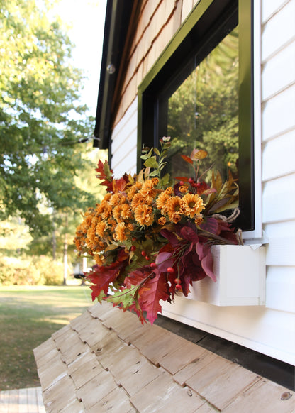 Artificial golden yellow mums arranged in a window box