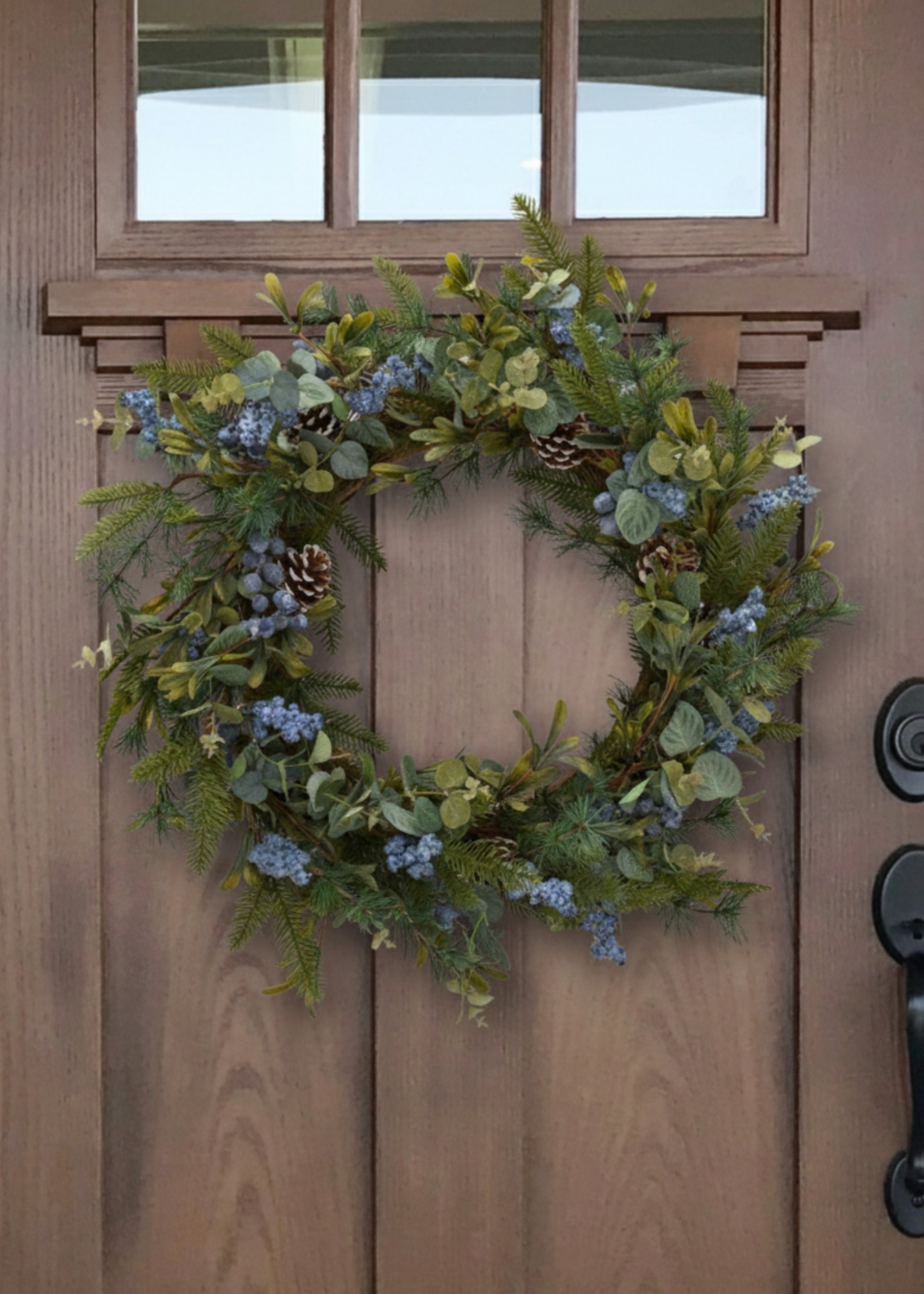 fake pine and blue berries wreath on door