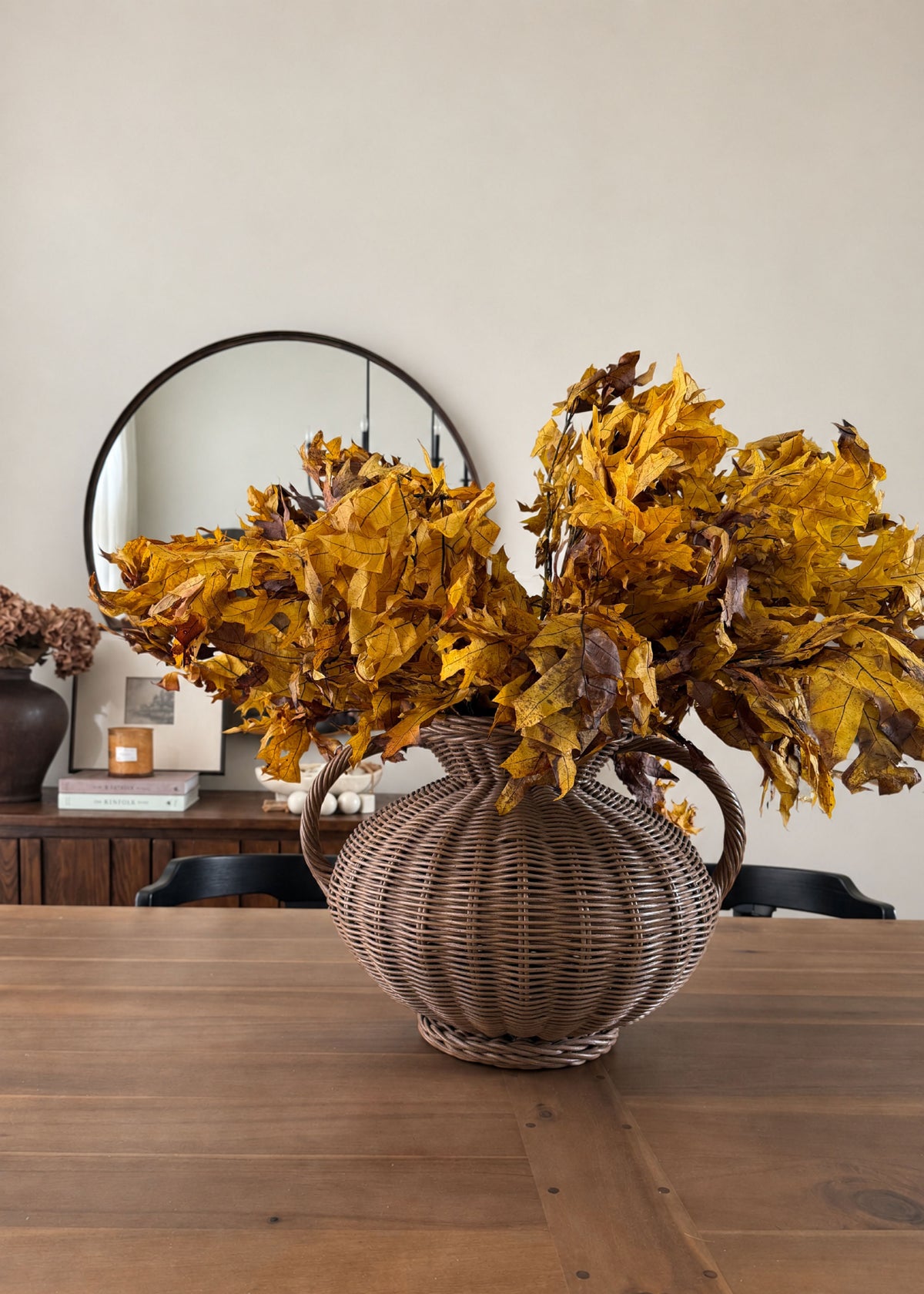 preserved fall leaves arranged in a wicker vase on a table