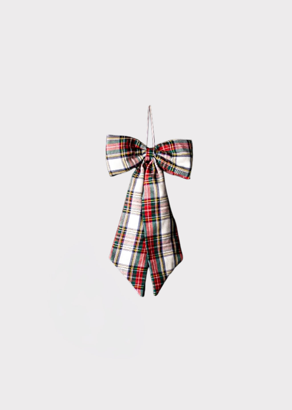 A tartan plaid bow ornament in a classic red, green, black, and white pattern, hanging against a solid light gray background.