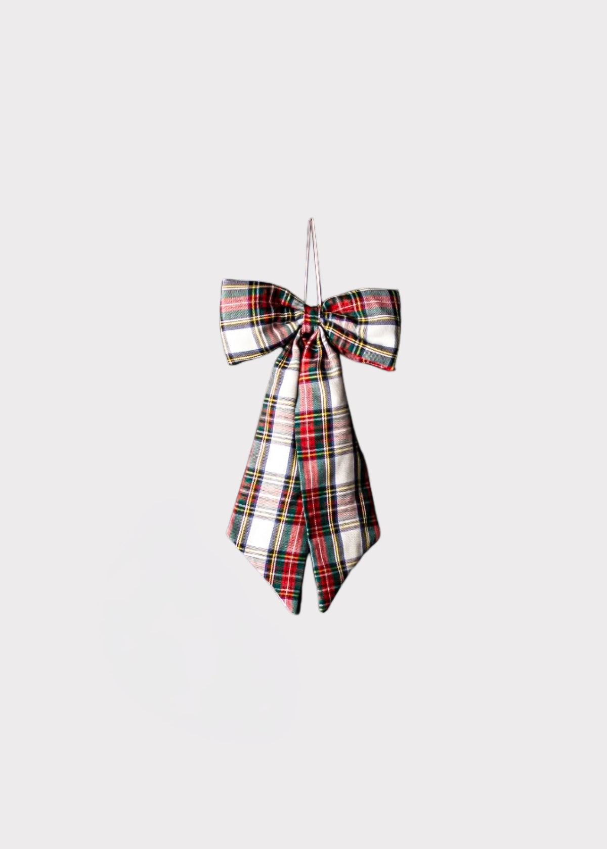 A tartan plaid bow ornament in a classic red, green, black, and white pattern, hanging against a solid light gray background.