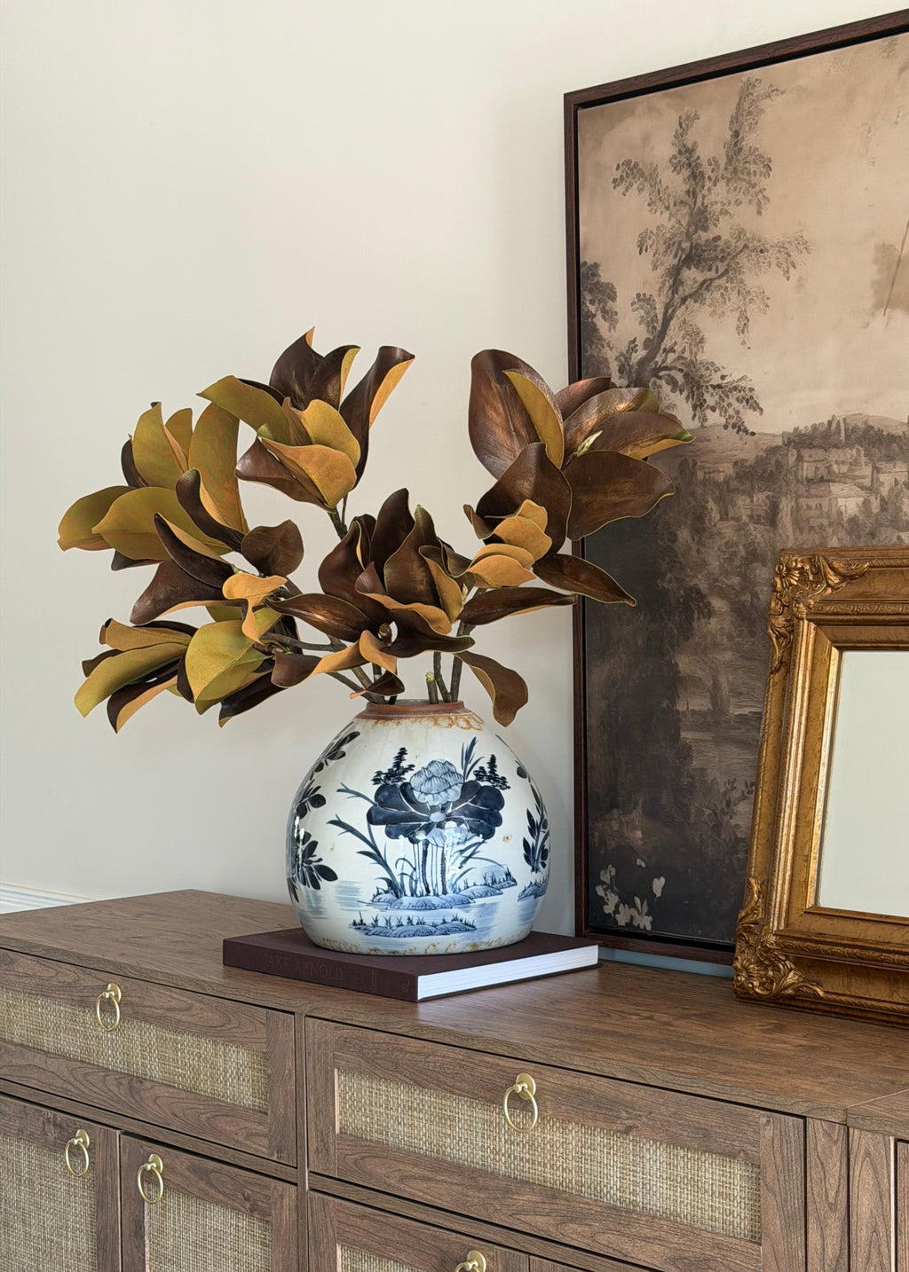 artificial brown magnolias styled on a wood credenza