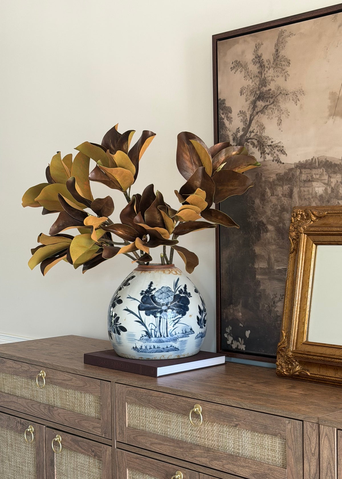 artificial brown magnolias styled on a wood credenza
