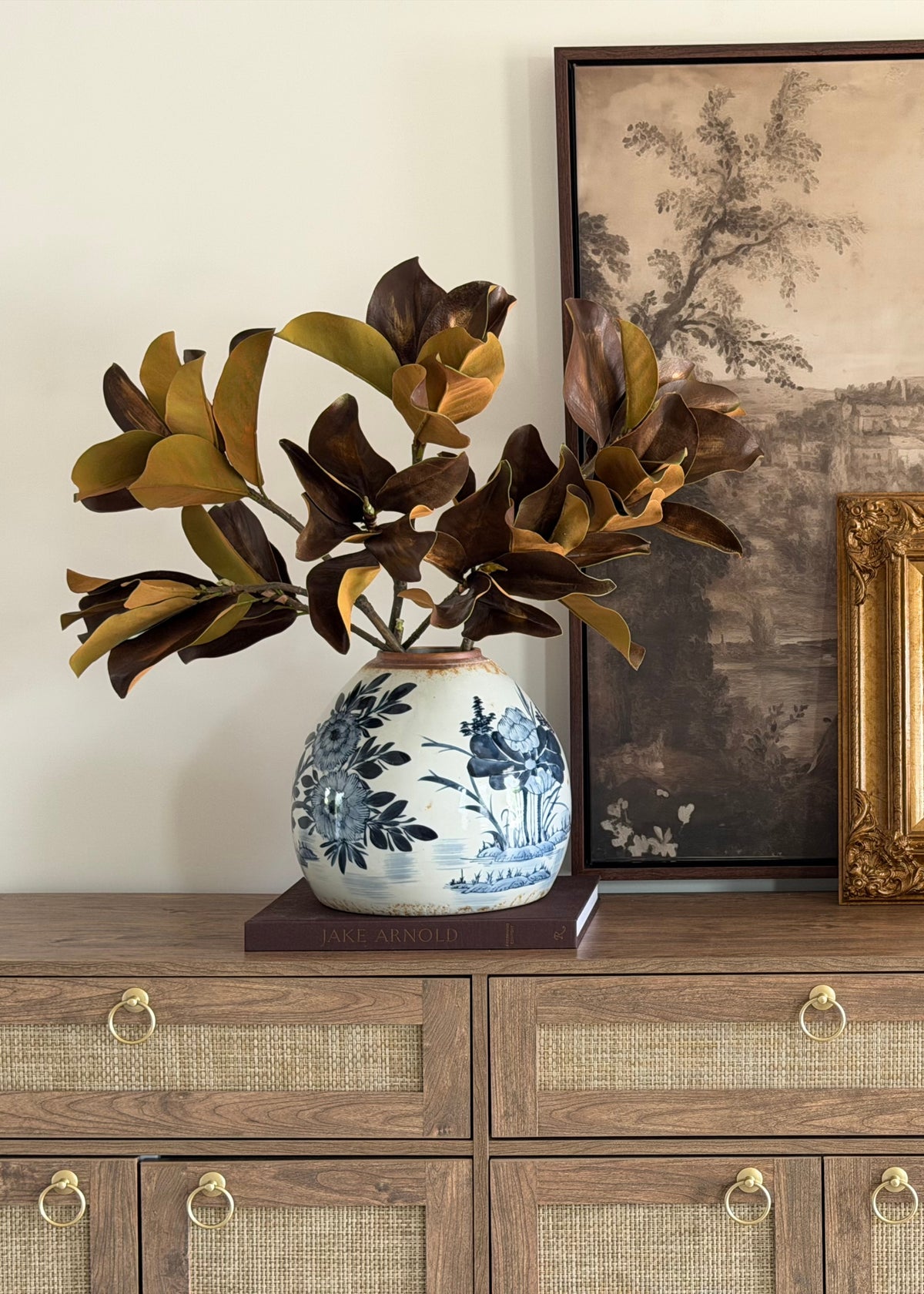 artificial brown and green magnolia leaf branches styled in a blue and white ginger vase