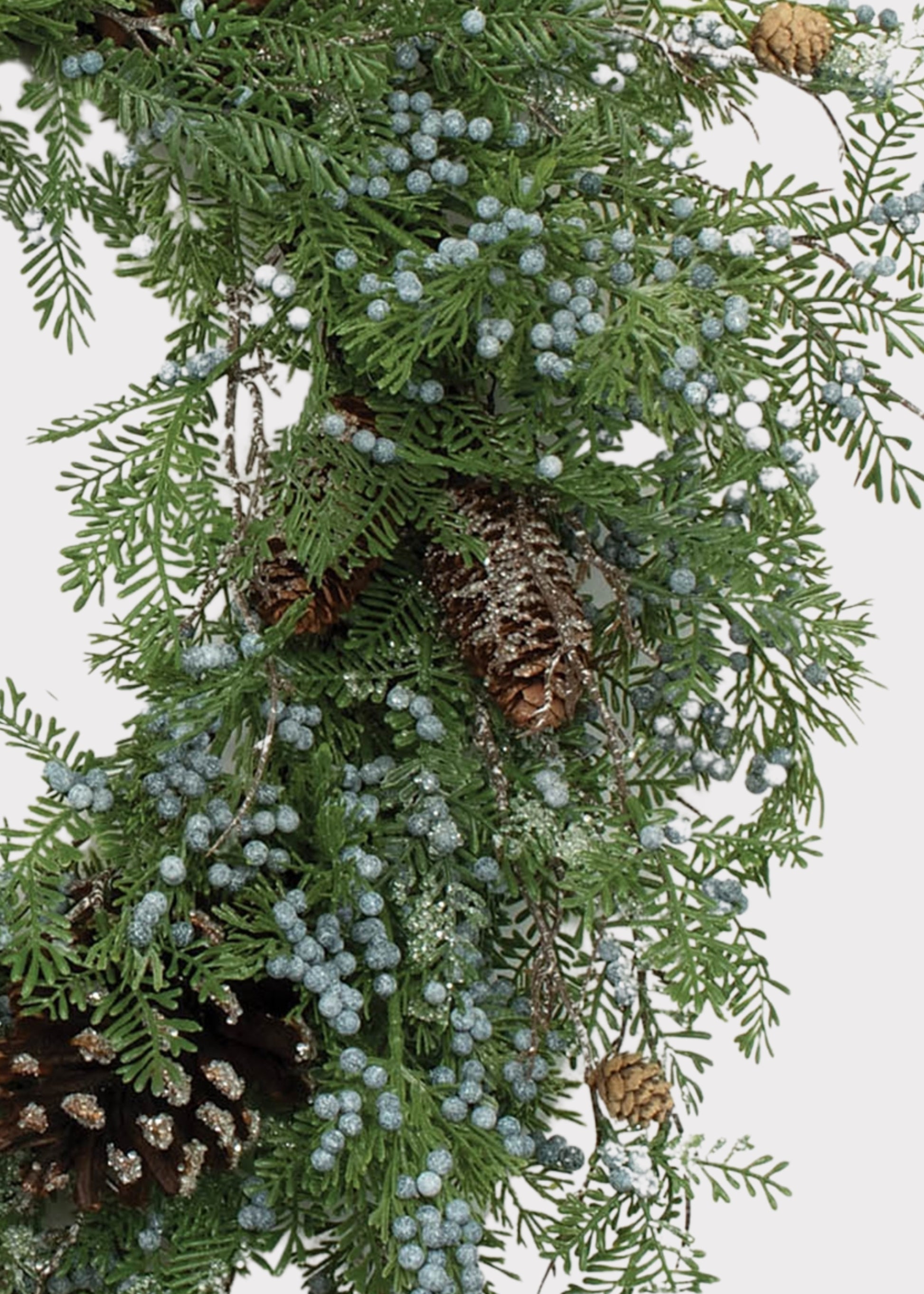 A close-up of a green evergreen wreath decorated with small pale blue berries and brown pinecones