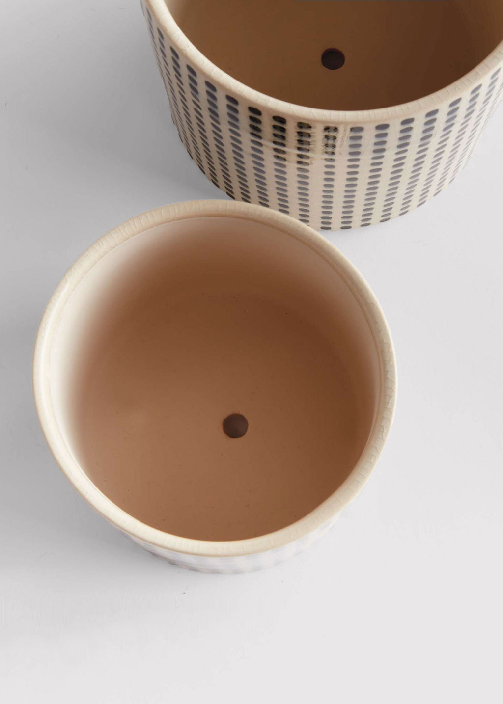 Openings of two ceramic pots with drainage holes