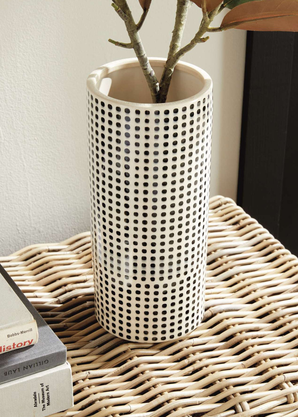 White vase with black dot pattern on a wicker surface
