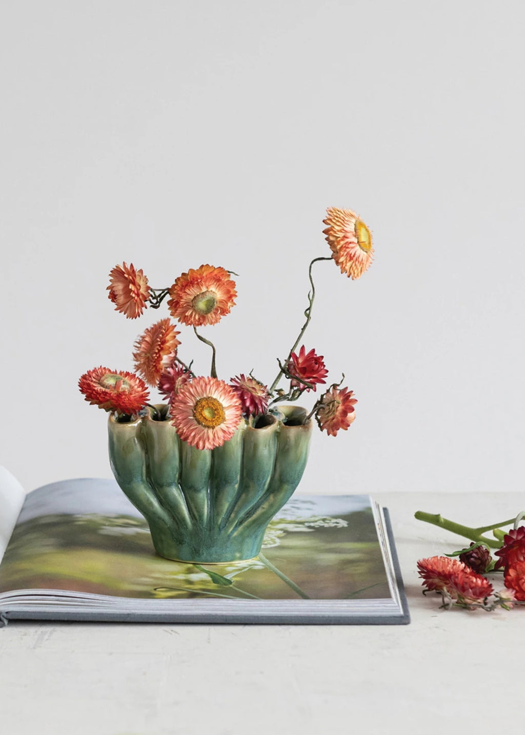 Decorative green vase with dried flowers on an open book 