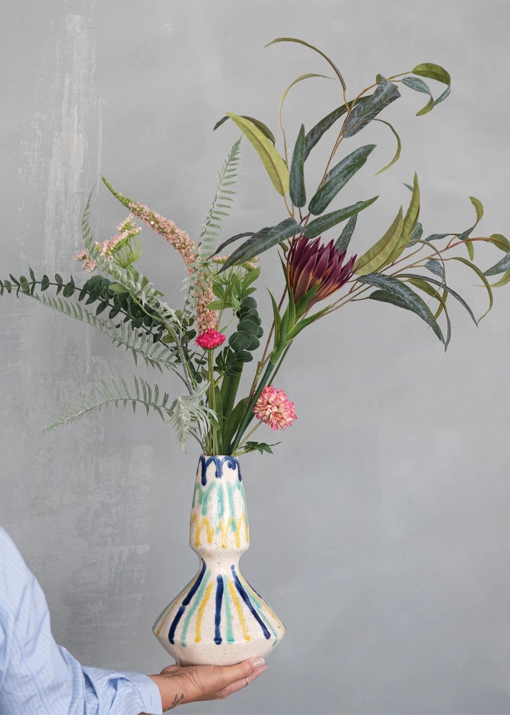 Person holding a colorful vase with flowers 